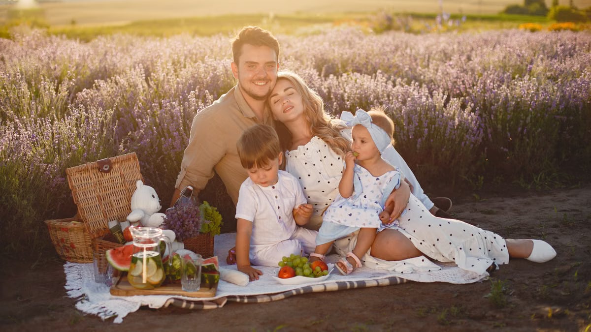 Happy family enjoying a peaceful picnic in a scenic lavender field at sunset.